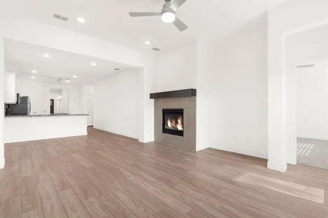 a view of an empty room with wooden floor and a fireplace