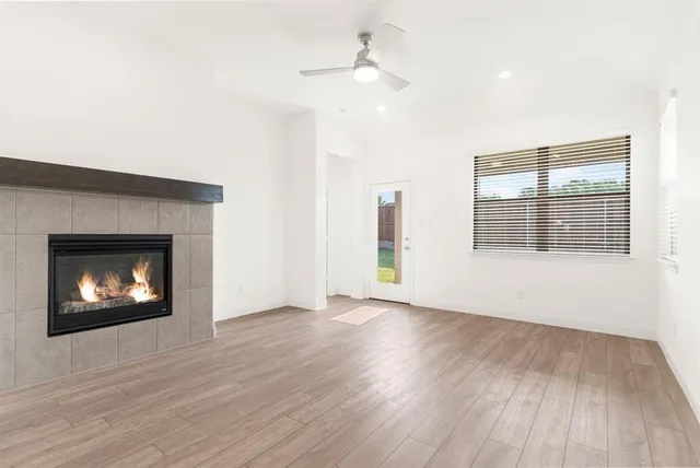 an empty room with wooden floor fireplace and windows