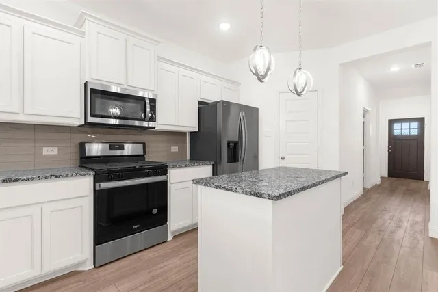 a kitchen with stainless steel appliances granite countertop a stove a refrigerator and a microwave