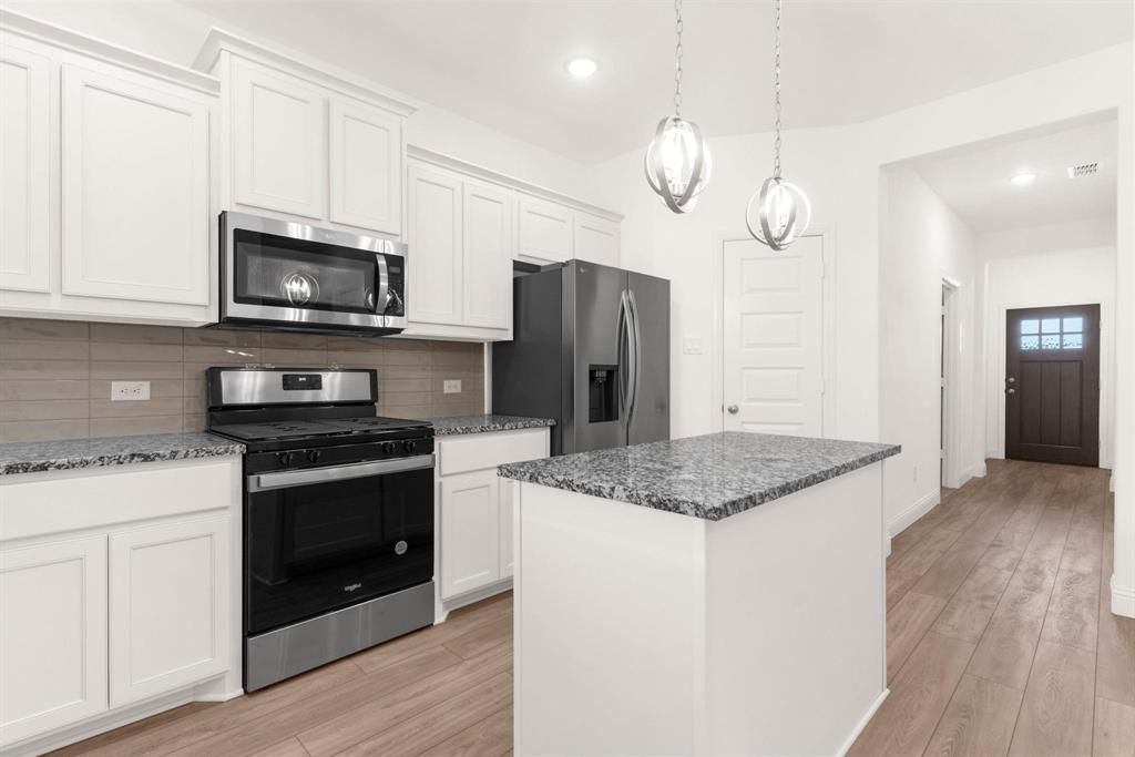 216 Town Pk Avenue Princeton, TX 75407 - Photo 6 of 19 a kitchen with stainless steel appliances granite countertop a stove a refrigerator and a microwave