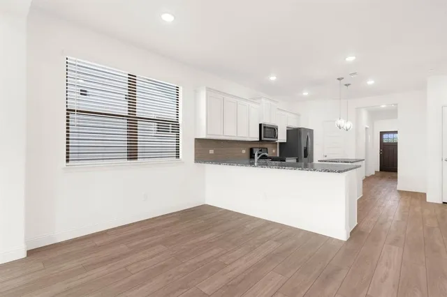 a view of kitchen with stainless steel appliances granite countertop a stove top oven a sink dishwasher and a microwave oven on wooden floors
