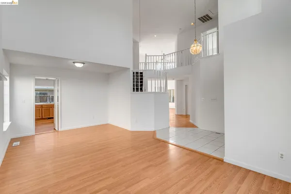 an empty room with wooden floor fireplace and windows