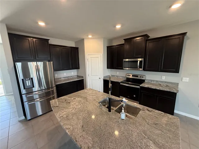 a kitchen with granite countertop a refrigerator and a stove top oven