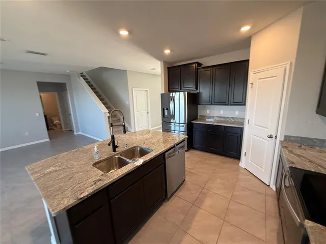 a kitchen with kitchen island granite countertop a sink stove and refrigerator