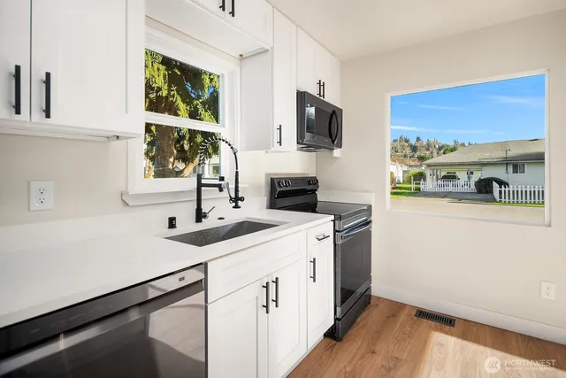 a kitchen with a sink and a stove top oven with wooden floor