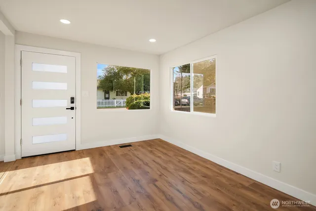 an empty room with wooden floor and windows