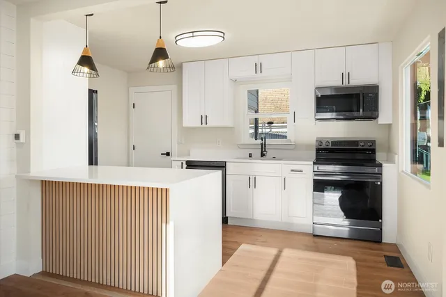 a kitchen with stainless steel appliances a stove a sink and white cabinets