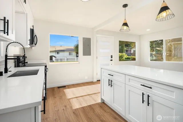 a kitchen with stainless steel appliances a sink stove and wooden floor