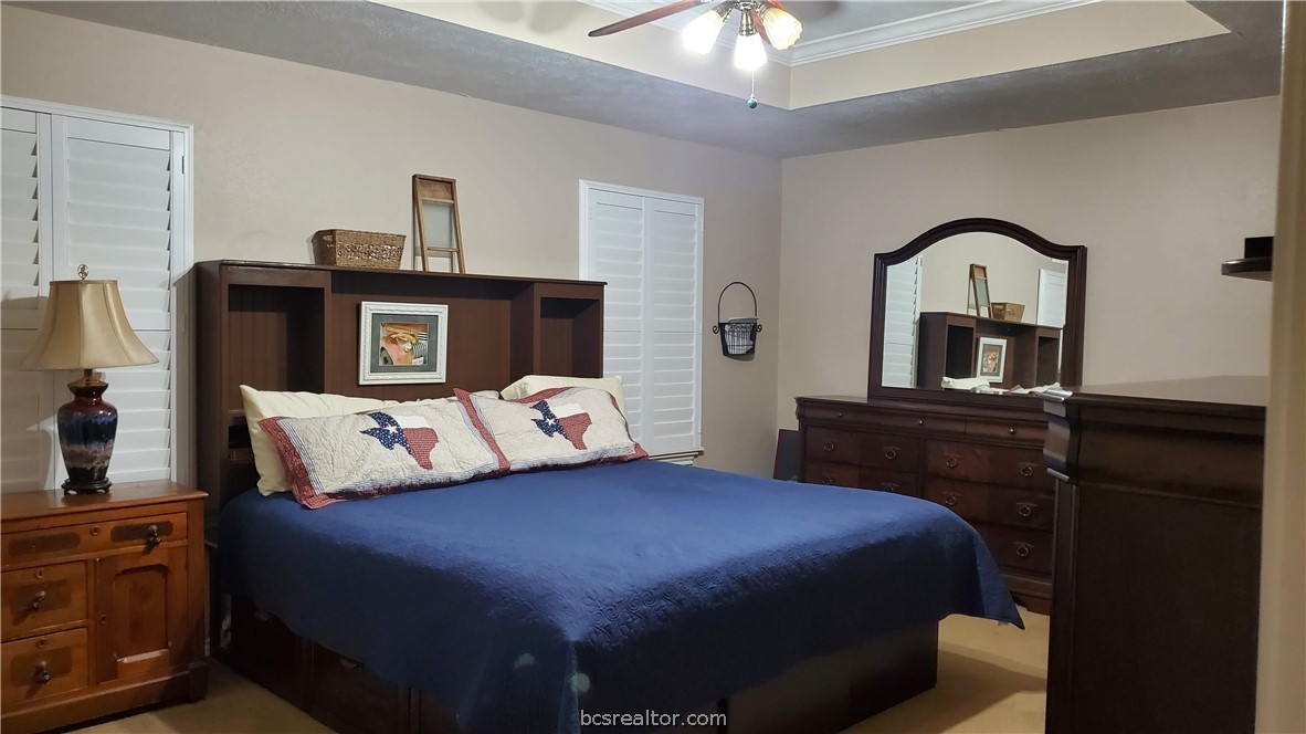 5660 Falling Water Bryan, TX 77808 - Photo 7 of 27 Carpeted bedroom featuring crown molding, ceiling fan, and a raised ceiling