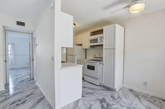 a kitchen with white cabinets and white appliances