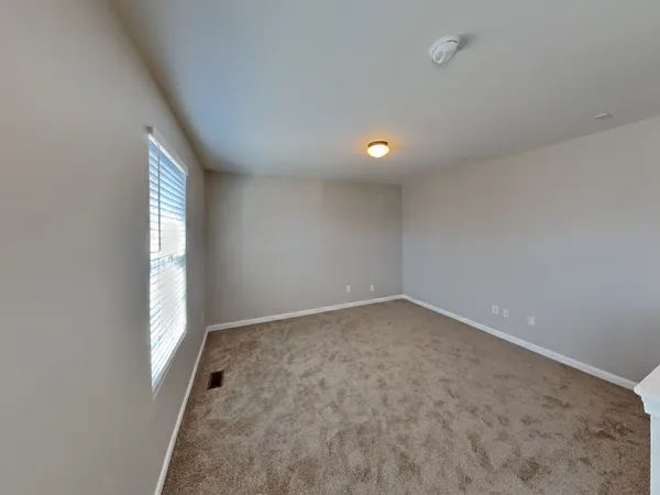 an empty room with a window and chandelier fan