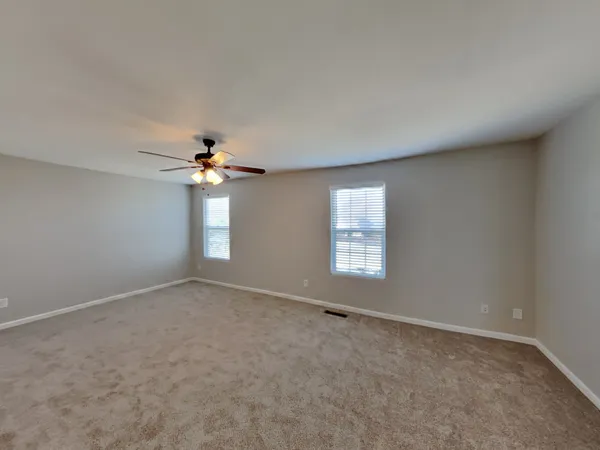 an empty room with windows and chandelier fan