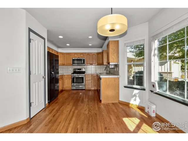 a kitchen with stainless steel appliances granite countertop a refrigerator a stove a sink dishwasher and white cabinets with wooden floor