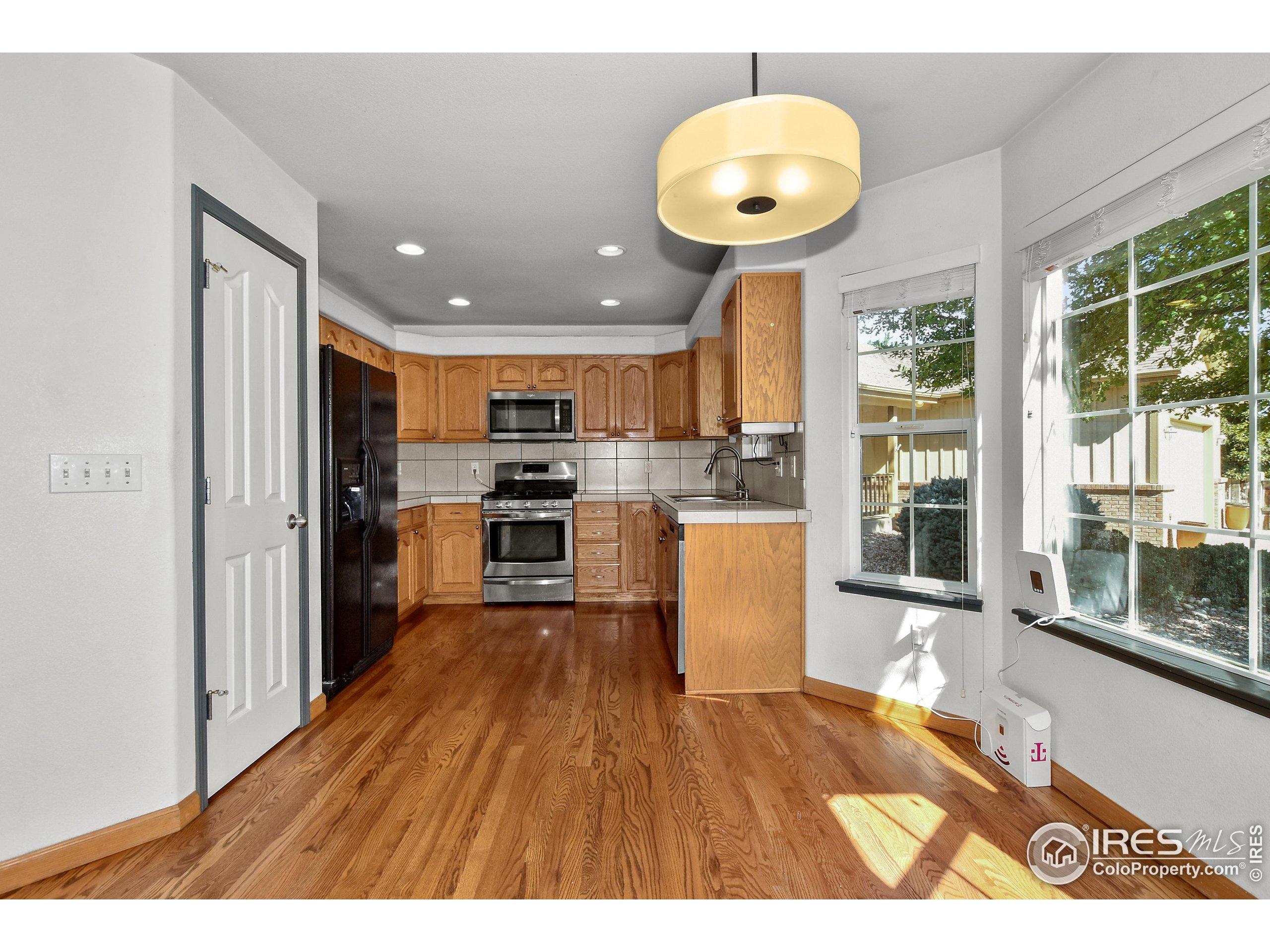 205 Timber Ridge Court Severance, CO 80550 - Photo 11 of 48 a kitchen with stainless steel appliances granite countertop a refrigerator a stove a sink dishwasher and white cabinets with wooden floor