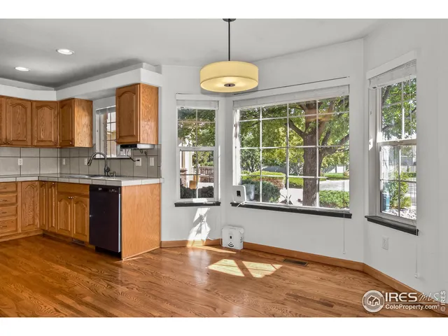 a kitchen with stainless steel appliances granite countertop a stove a sink dishwasher a refrigerator and a dining table with wooden floor