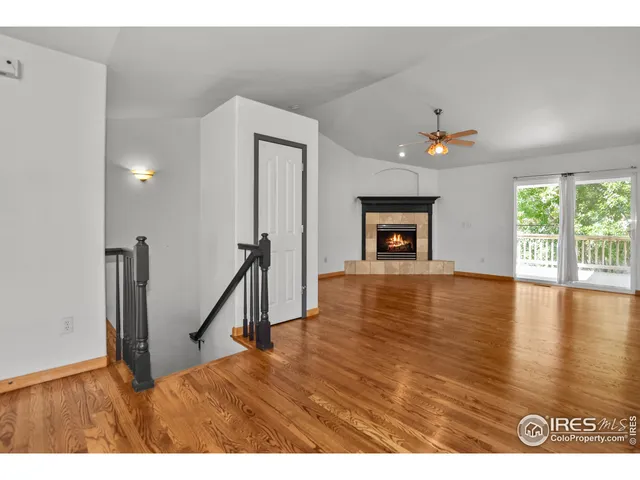 a view of empty room with wooden floor fireplace and window