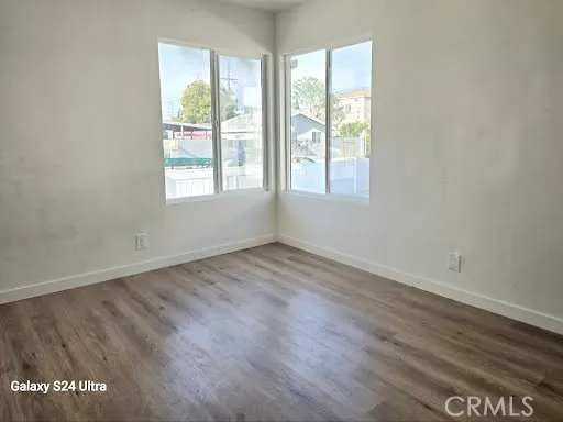 an empty room with wooden floor mirror and windows