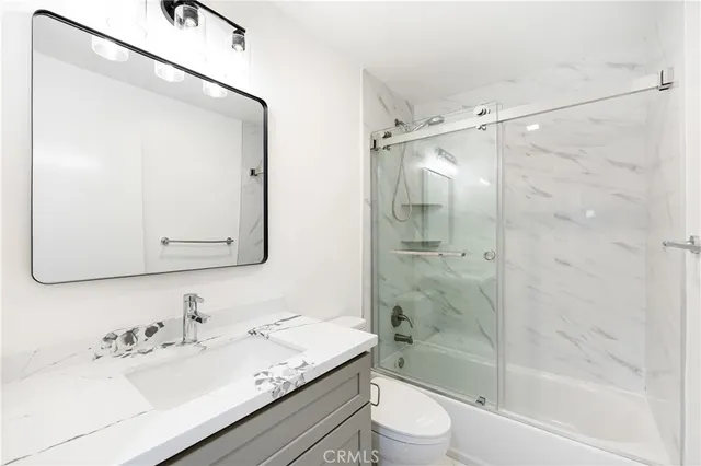 a bathroom with a granite countertop sink mirror toilet and bathtub