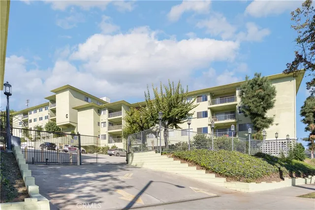a front view of a building with street view and trees