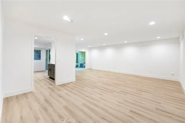 an empty room with wooden floor and natural light
