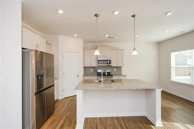 a kitchen with stainless steel appliances granite countertop a sink a stove and a wooden floors