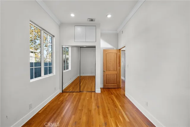 a view of empty room with wooden floor and fan