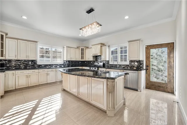 a large kitchen with kitchen island granite countertop a stove a sink a refrigerator and white cabinets