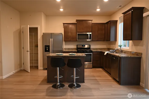 a kitchen with stainless steel appliances granite countertop wooden cabinets a refrigerator a stove a sink and a microwave