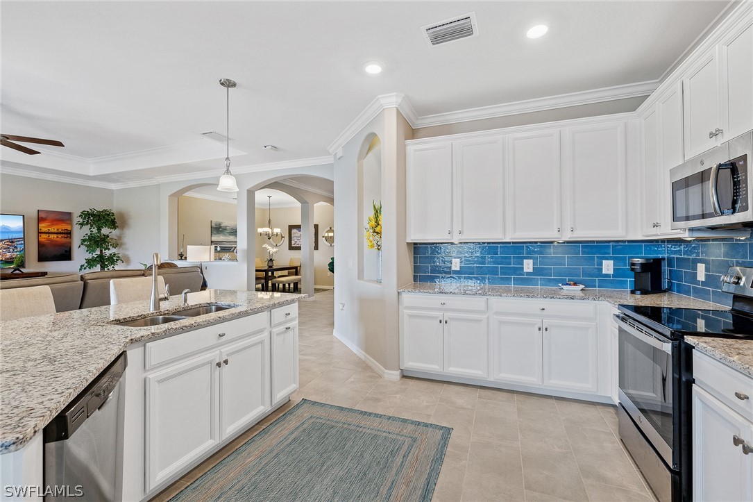 19729 Beechcrest Place Estero, FL 33928 - Photo 11 of 45 a kitchen with granite countertop kitchen island a sink stainless steel appliances and cabinets