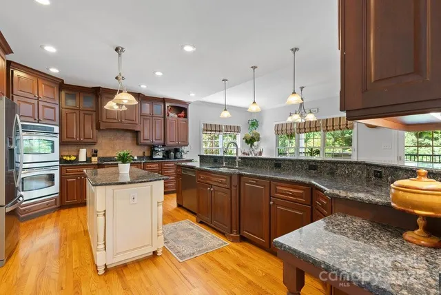 a kitchen with stainless steel appliances granite countertop a sink a stove top oven a counter space and cabinets