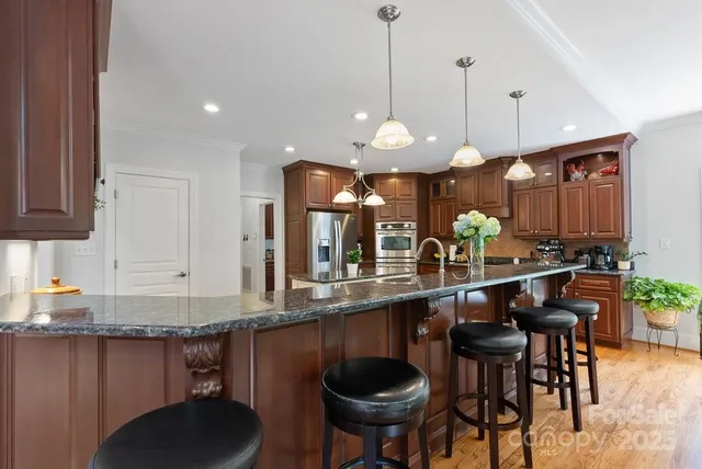 a kitchen with stainless steel appliances granite countertop a sink a stove a table and chairs
