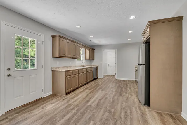 a kitchen with granite countertop a refrigerator sink and cabinets