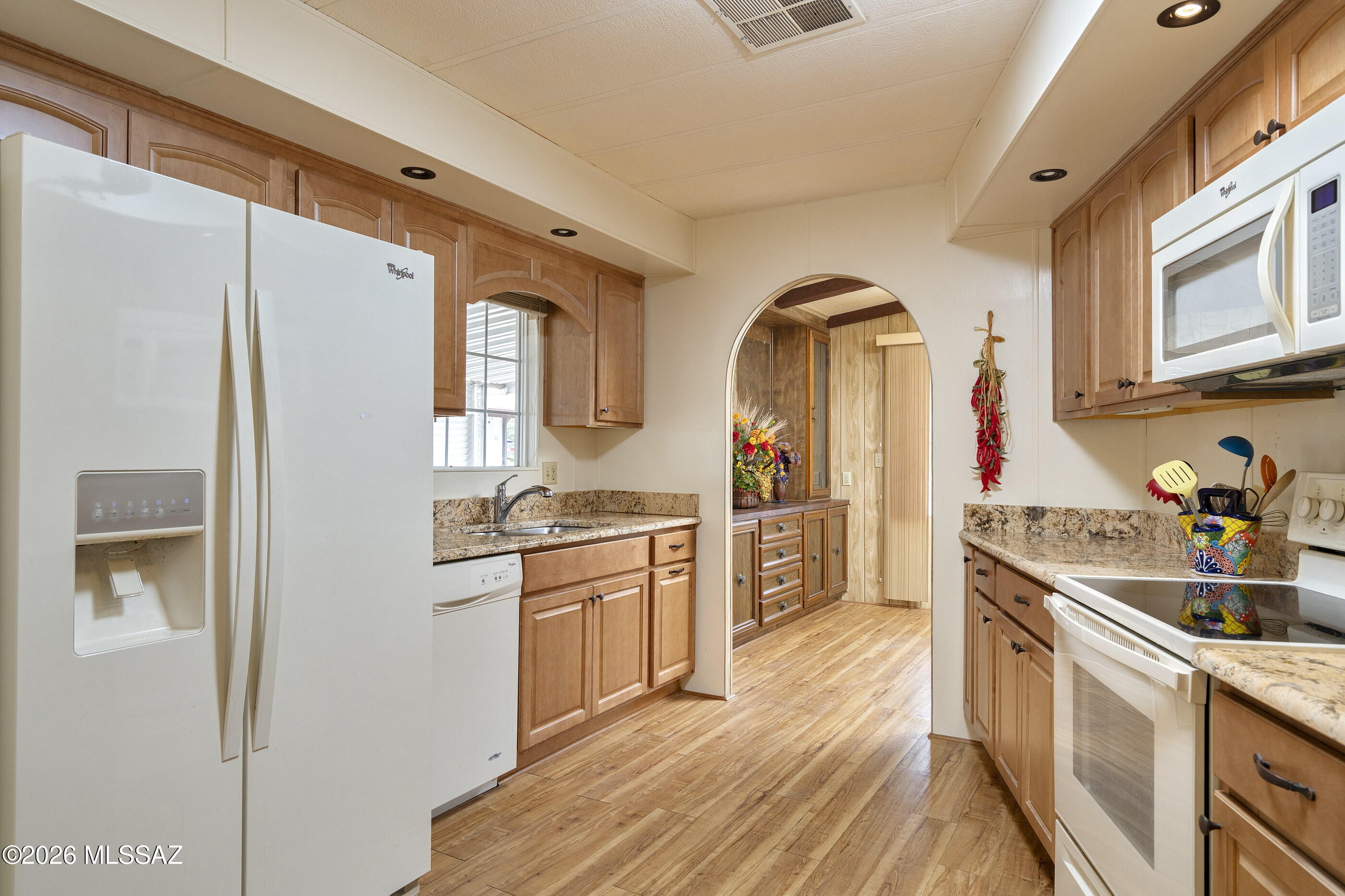 6121 West Flying M Street Tucson, AZ 85713 - Photo 2 of 25 a kitchen with stainless steel appliances granite countertop a refrigerator a stove and a sink with wooden floor