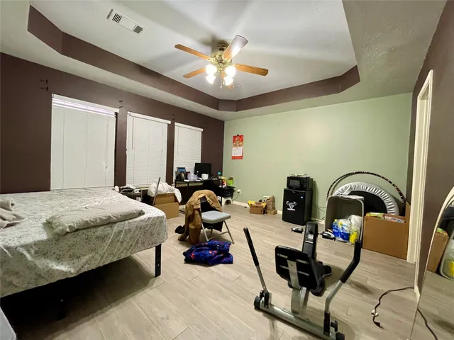 a bedroom with bed a large window with potted plants on the dresser