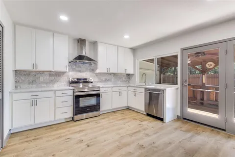 a kitchen with granite countertop a stove top oven sink and cabinets