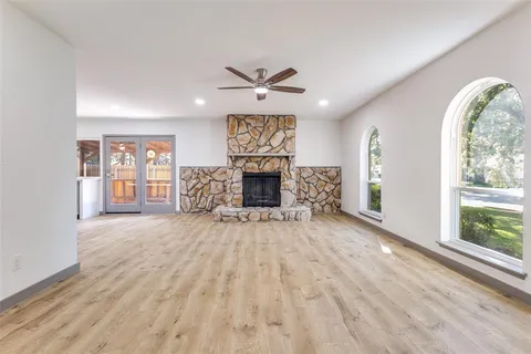 an empty room with windows fireplace and wooden floor