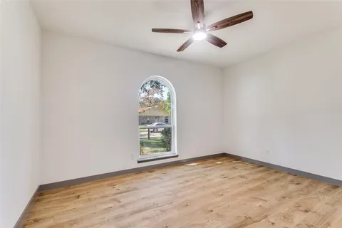 an empty room with a window and ceiling fan