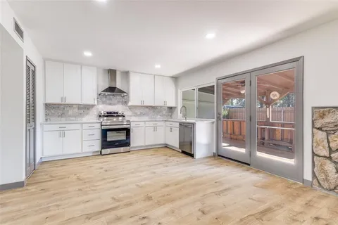 a open kitchen with granite countertop a stove top oven a sink and cabinets