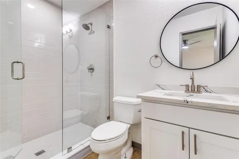 a bathroom with a toilet sink vanity granite and shower