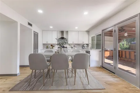 a living room kitchen with a dining table wooden floor and a large window