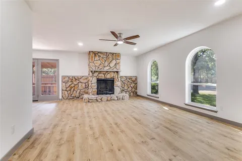an empty room with windows chandelier fan and fireplace