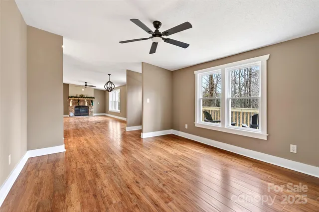 a view of empty room with wooden floor and ceiling fan