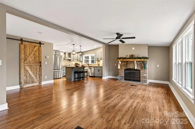 a view of a livingroom with furniture a fireplace wooden floor and a window