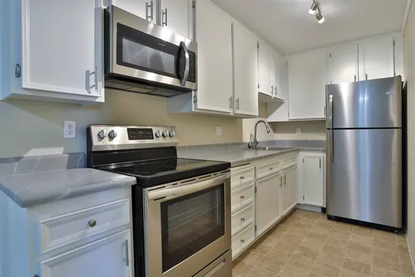 a kitchen with stainless steel appliances granite countertop white cabinets a refrigerator a stove a sink and white cabinets