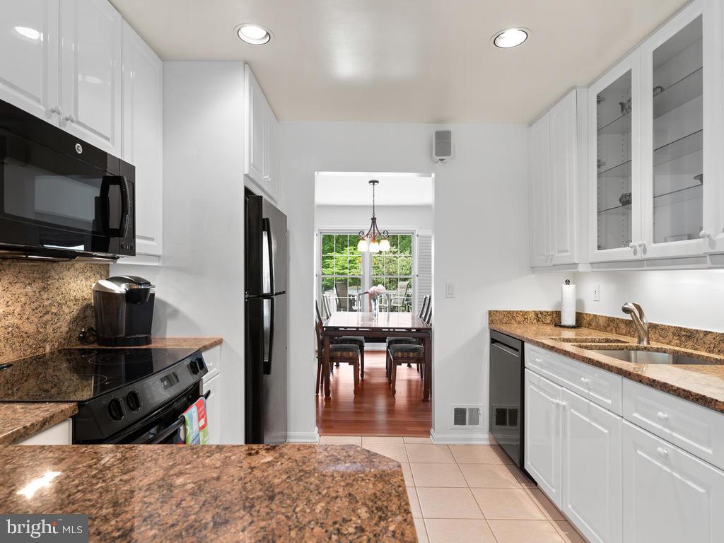 600 Bryants Nursery Road Silver Spring, MD 20905 - Photo 24 of 60 a kitchen with stainless steel appliances granite countertop a refrigerator a sink dishwasher a stove and a dining table with wooden floor