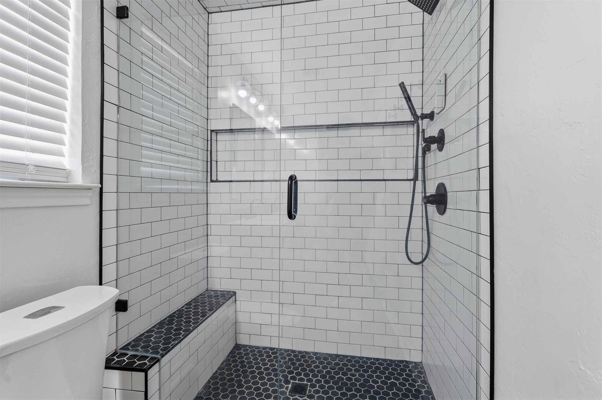 831 Barrons Ridge Wilson, OK 73463 - Photo 20 of 47 Enclosed shower featuring subway tile walls, a built-in bench, hexagon tile flooring, a recessed shower niche, and matte black fixtures