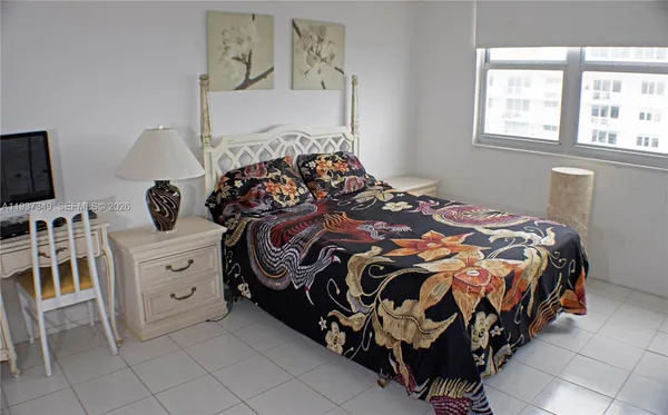 a bedroom with a bed and a flat tv screen on the dresser