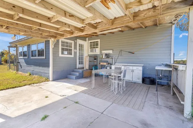 a view of a patio with table and chairs near a barbeque