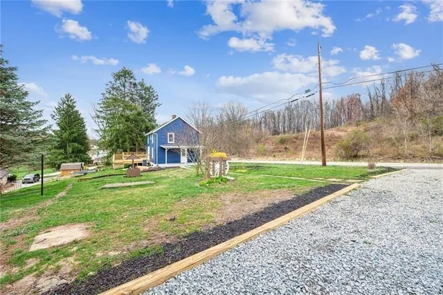 a view of a house with a yard and a large tree