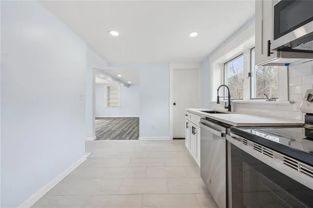 a large kitchen with granite countertop a sink and a stove top oven with wooden floor